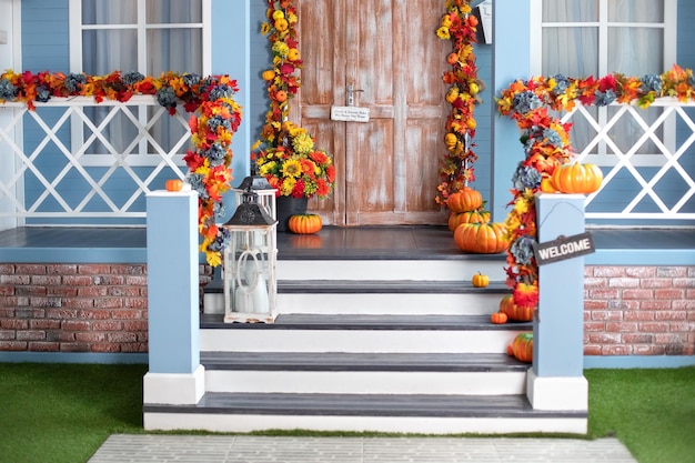 秋の休日の秋の花とハロウィーンのカボチャのために飾られた家の入り口の階段