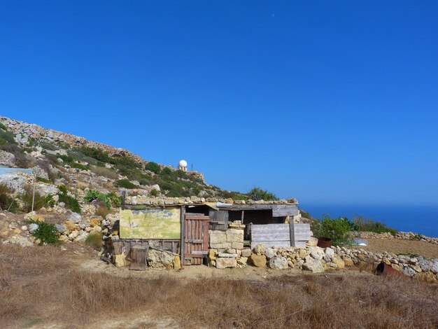 House on field against clear blue sky