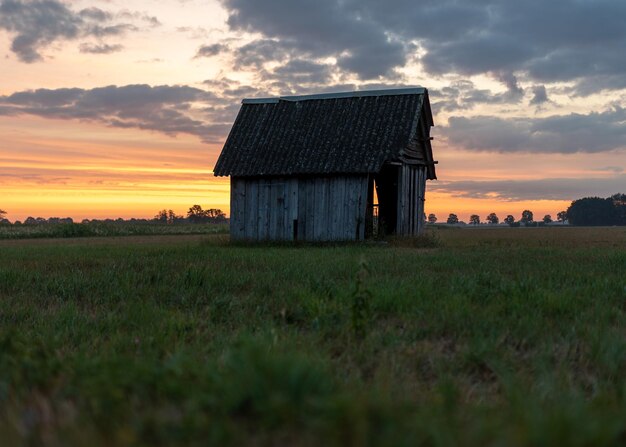 House on field against sky during sunset