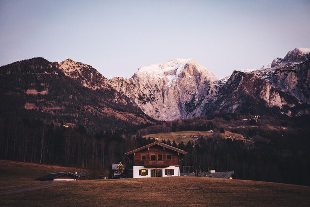 Photo house on field by rocky mountains against clear sky