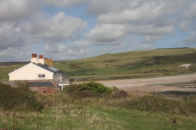 A house in a field with a hill in the background