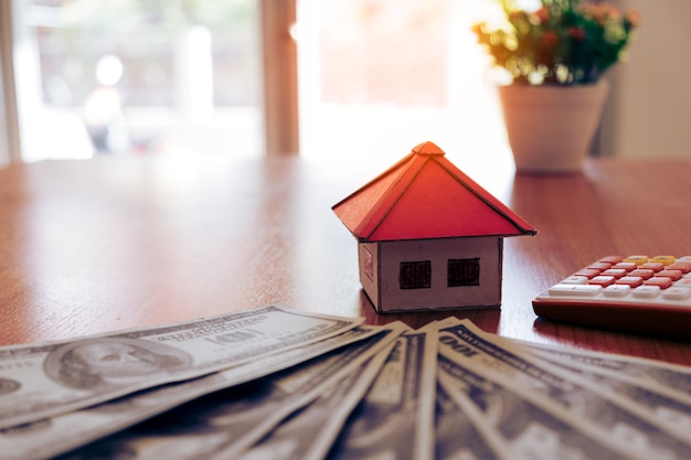 House from the paper and money on wooden background