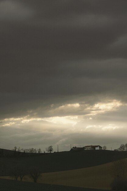 Photo a house on a hill with a sky that has the sun shining through it