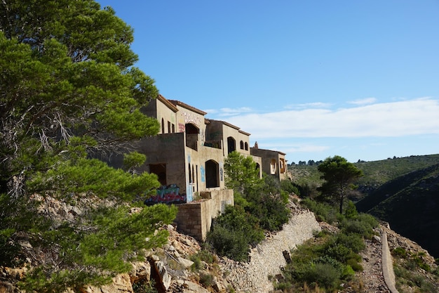 A house on a hill with trees in the foreground