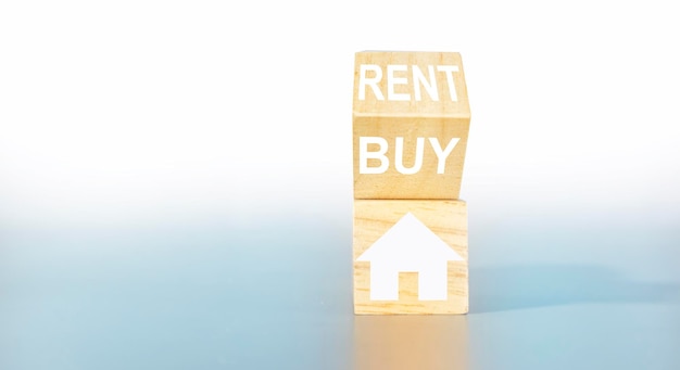 House icon and rent or buy on wooden box light gray\
backgrounddeciding to buy a home or rent a home