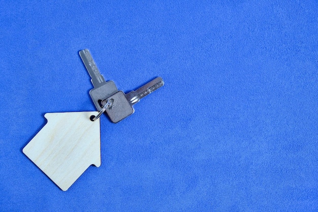 Photo house keys keychain on blue background concept buy rent loan apartment or house.