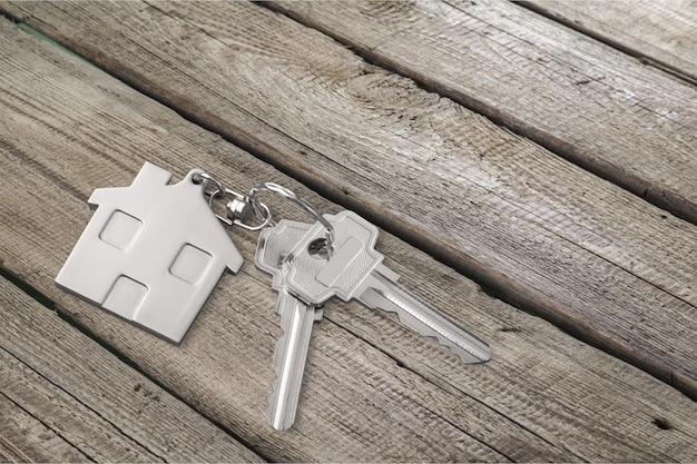 House keys with trinket on wooden background