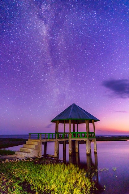 House on lake against sky at night