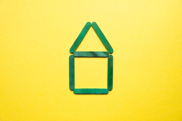 Photo a house made of green wooden sticks on a yellow background