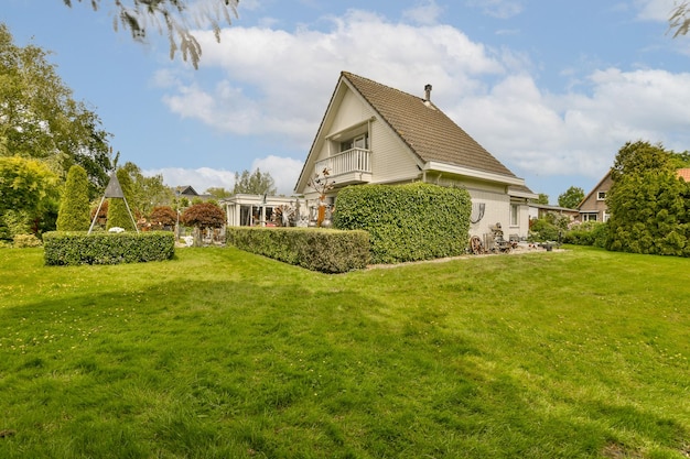 Photo a house in the middle of a grassy area with trees and bushes around it on a sunny summer day