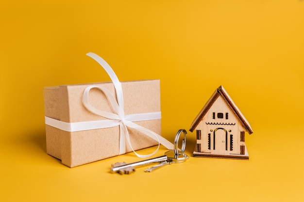 House miniature model, gift and keys on a yellow background. Investment, real estate, home, housing