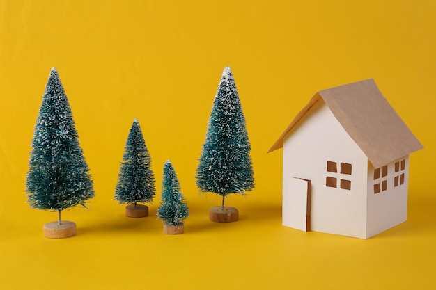 House model and a Christmas tree on yellow background