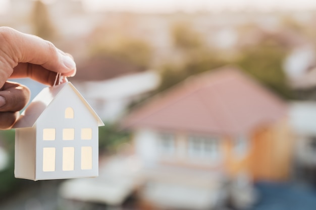 Modello di casa nella mano dell'agente del broker di assicurazione casa o nella persona del venditore.