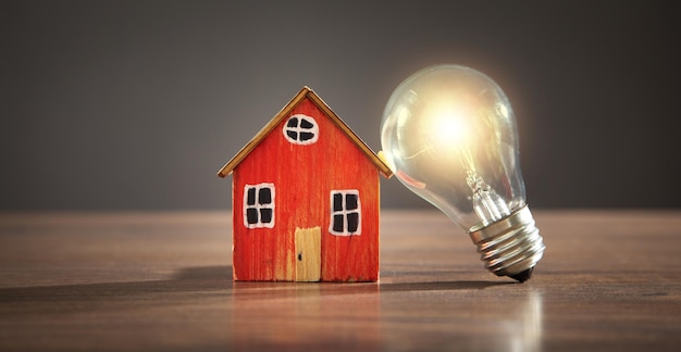 House model and light bulb on the wooden table