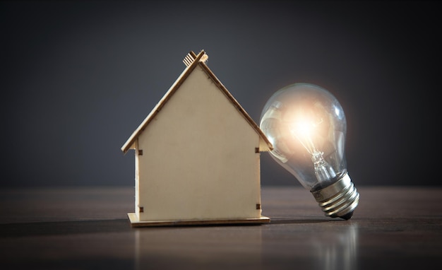 House model and light bulb on the wooden table