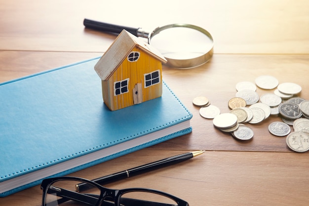 House model on notebook with coins on table