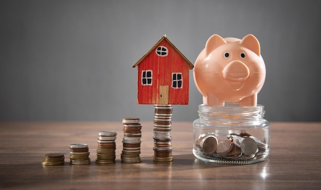 House model piggy bank and coins on the wooden table