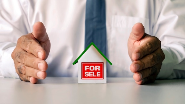 House model placed on desk and businessman hands enveloping financial concept home model. Mortgage and real estate