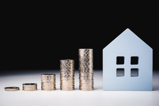 House model and row of coin money on white table