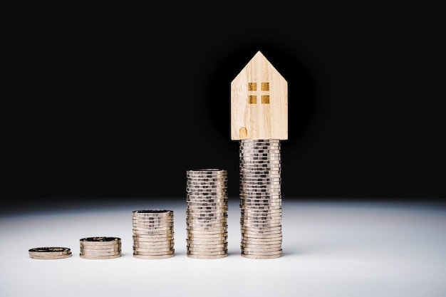 House model and row of coin money on white table 