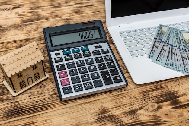 House model with dollars, laptop and clipboard