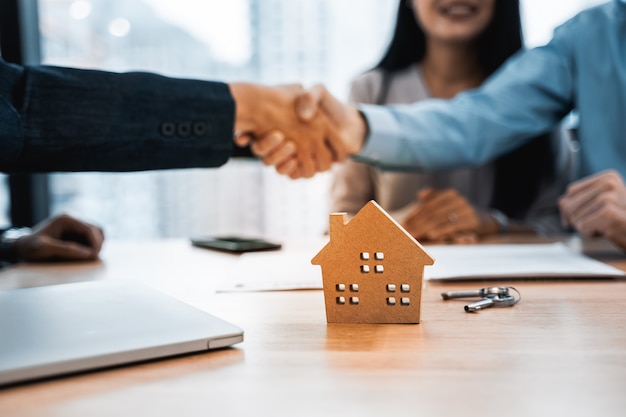 不動産業者と連絡を取り、家を購入して握手する顧客契約を持つ家モデル