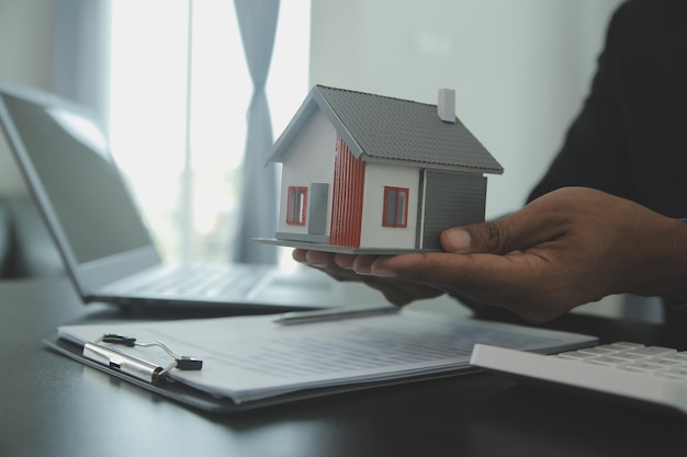 住宅保険の購入や不動産ローンのコンセプトの契約について話し合う不動産業者と顧客のいる住宅モデル