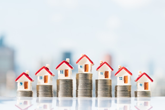 Photo house models on top of coins stack with city backgrounds.