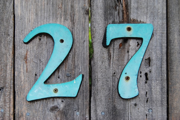 House number 27 sign on grey wooden fence