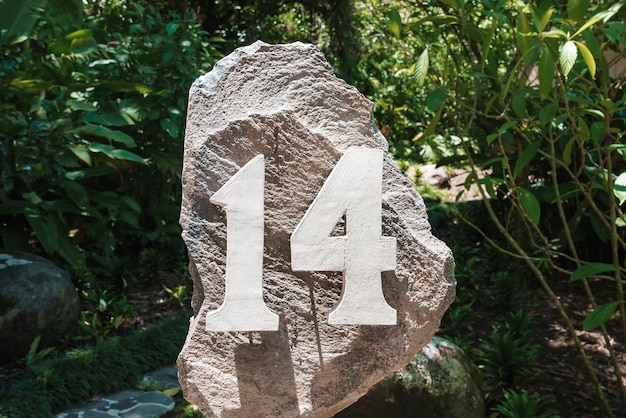 Photo house number installed on a big rock in the garden of residence