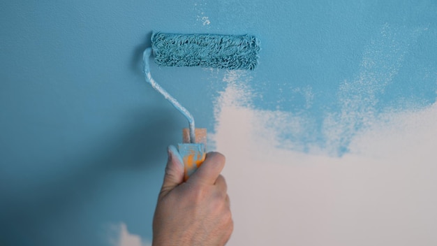 House painter paints wall blue with roller closeup repair and painting walls concept