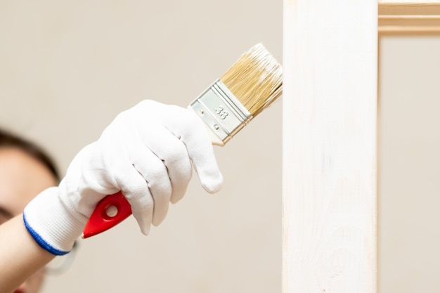 A house painter paints a wood with a brush