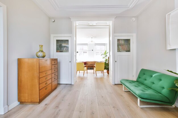 House pass through sitting room with stylish gray couch and wooden chest of drawers near doorway to living room