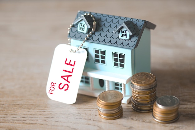 Photo house for sale coins stack and house model on sale with hang tag or real estate home and commercial building loan business finance economy commercial real estate investments concept