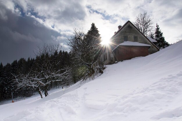 House on snow covered field against sky