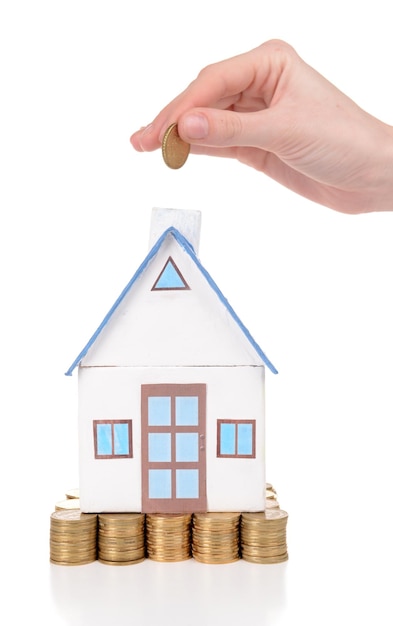 House standing on heap of coins isolated on white