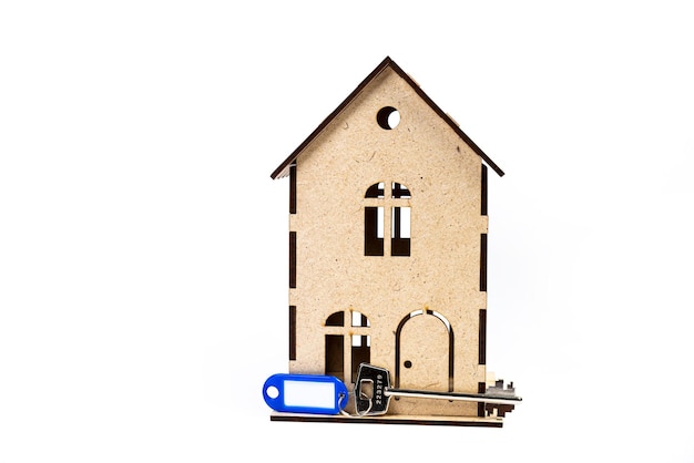 白い背景の上の金属の鍵と家のシンボル 不動産保険の概念 住宅ローン購入販売家の不動産業者の概念