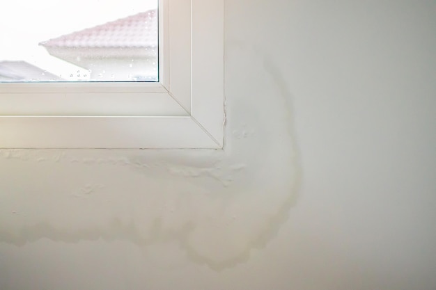 House wall near the window with some water stain show peeling paint