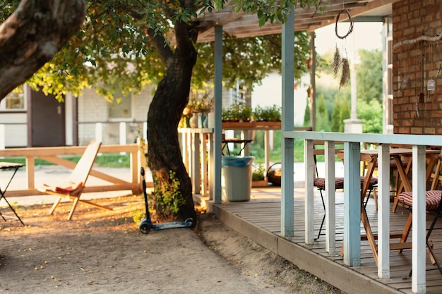 Дом с открытой террасой с деревянной садовой мебелью для отдыха в летний день