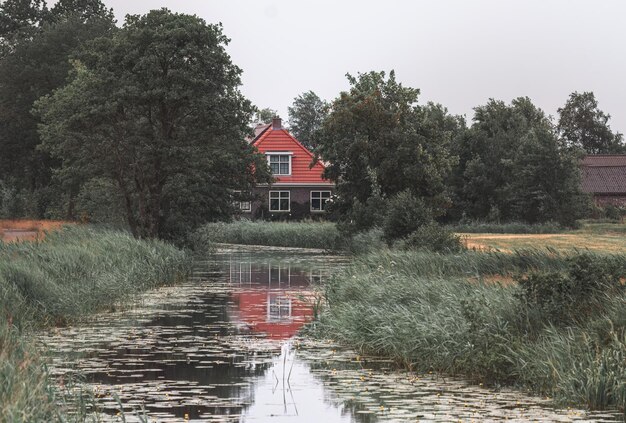 house with a red roof on the banks of a river in the Netherlands