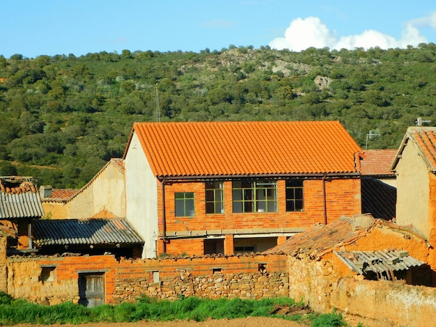 A house with a red roof and a green hill in the background.