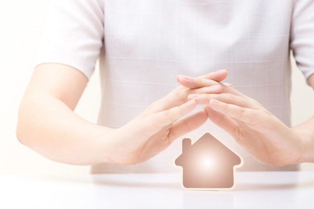 Foto casa sotto le mani della donna. assicurazione e concetto di protezione della casa.