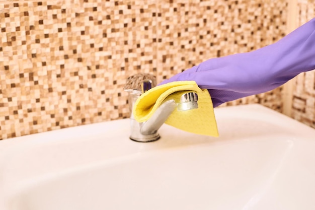 Foto lavoratore di casa, bagno pulito, guanto viola con straccio giallo.