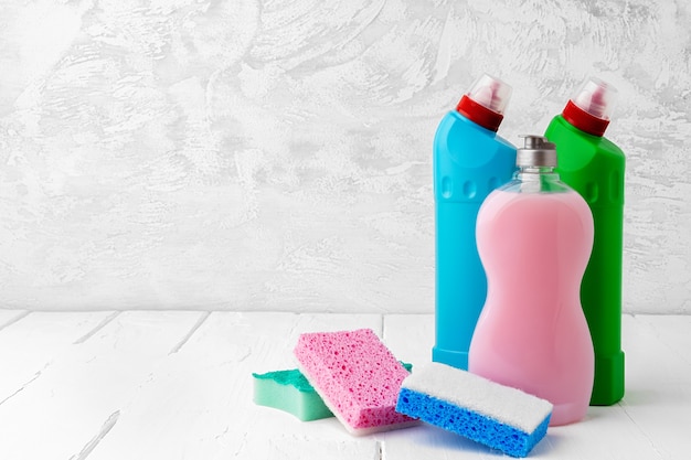 Household cleaning detergents on wooden table against gray background