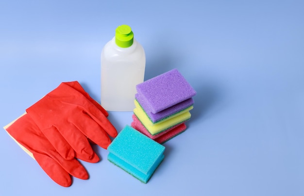 Household gloves sponges detergent on blue background