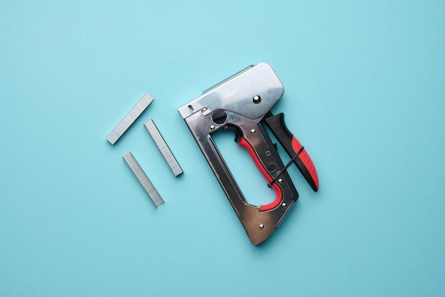 Household manual stapler and staples on a blue background top view