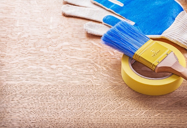 Household tape paint brush gloves on wooden board with copyspace