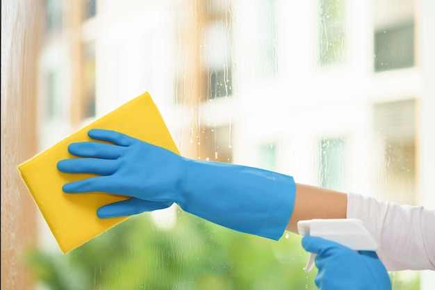 Housekeeper cleaning mirror with yellow cloth.