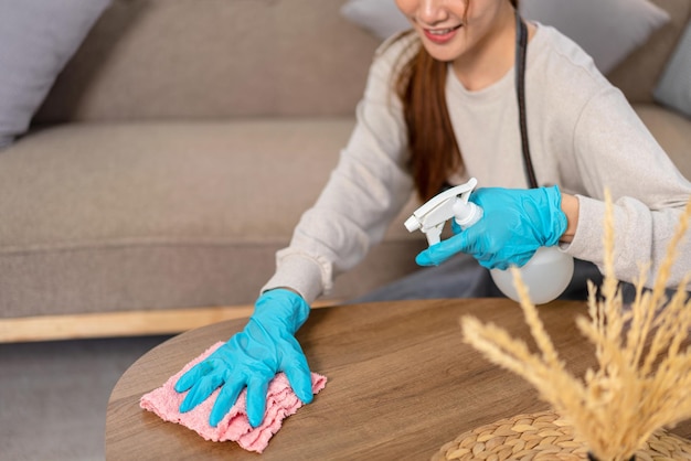 Housekeeper is wear protective gloves and using microfiber cloth with spray cleanser for cleanups