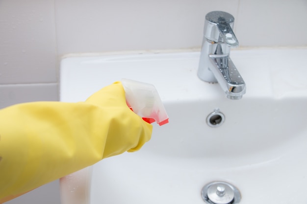 Housemaid waring yellow glove rubber clenning basin with spray bottle